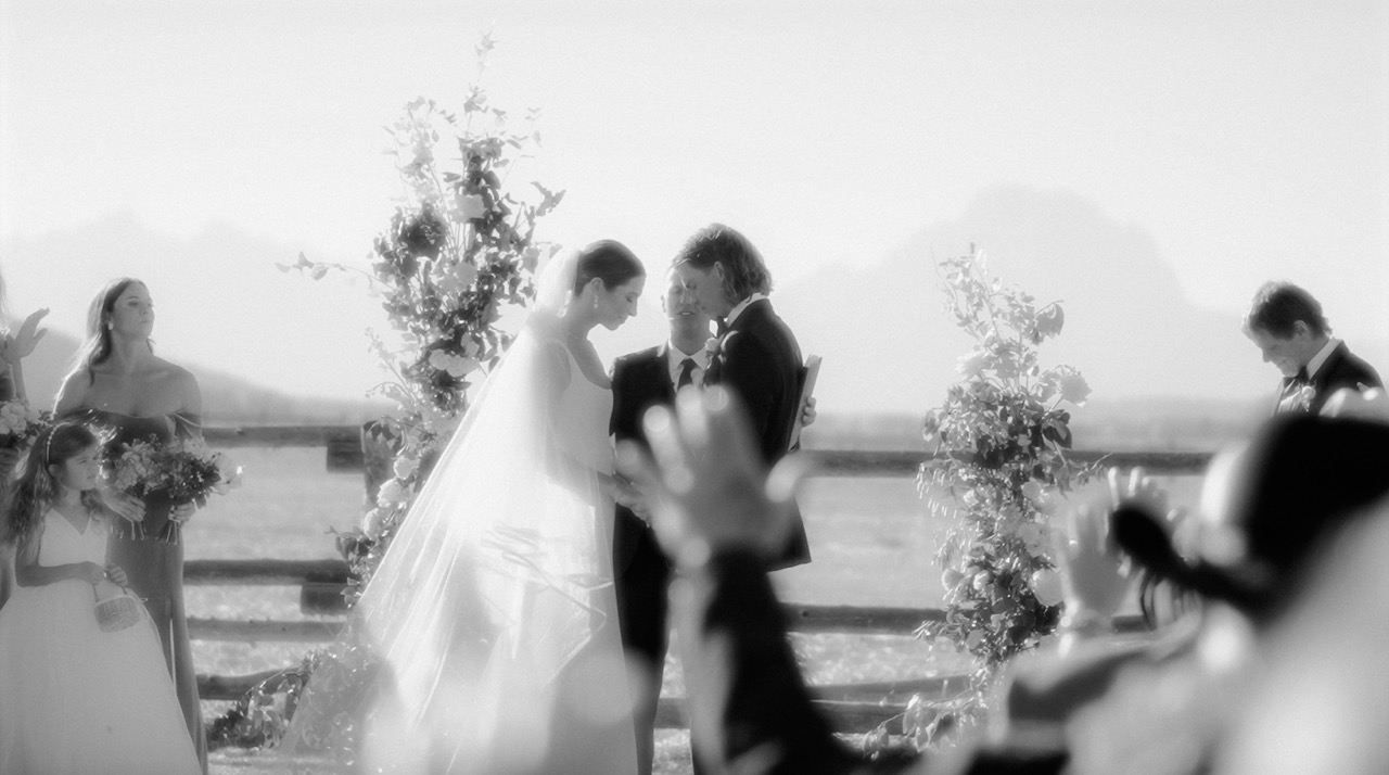 A couple at their wedding ceremony as their guests look on
