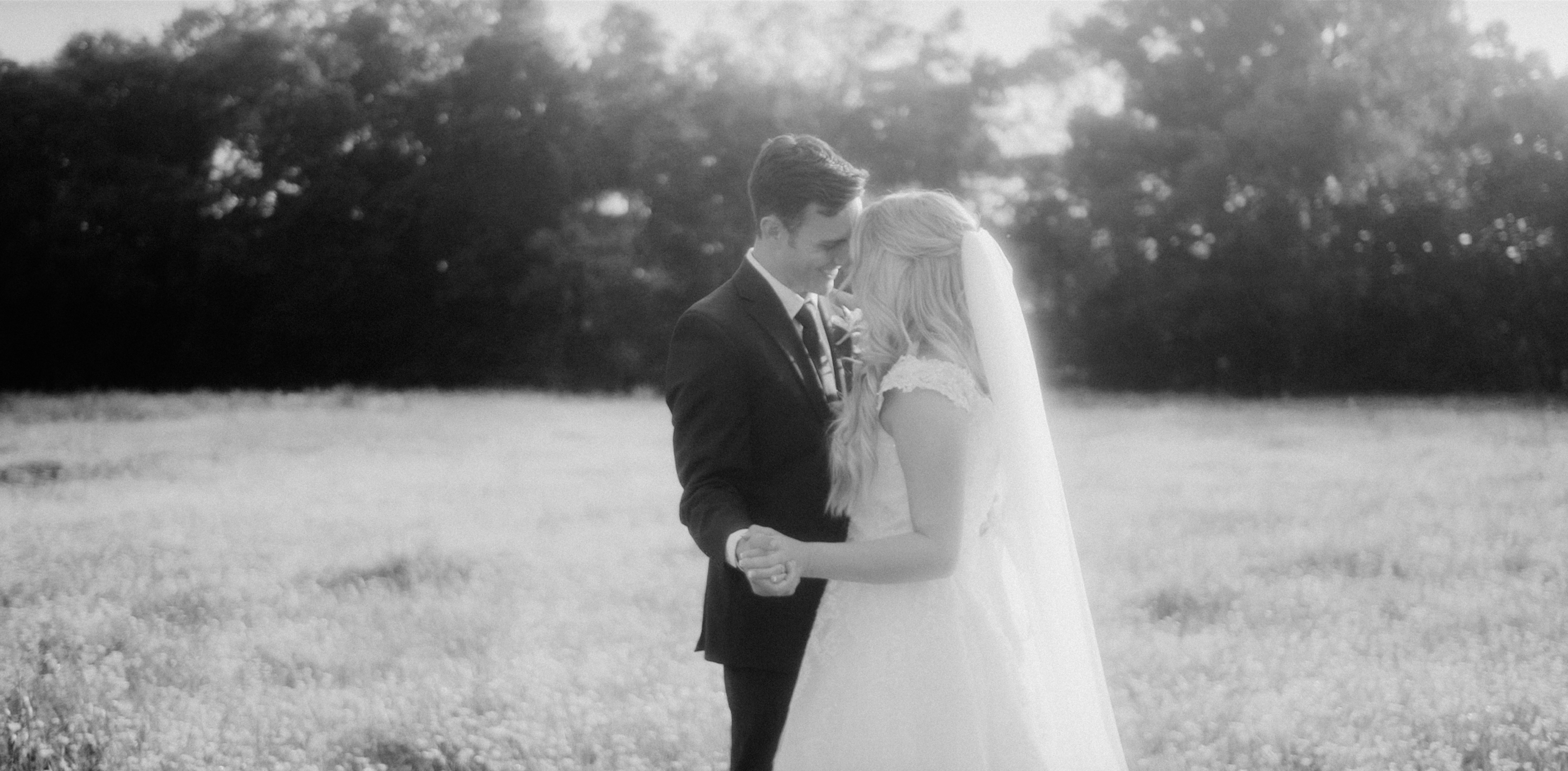 A bride and groom standing close together in an open field